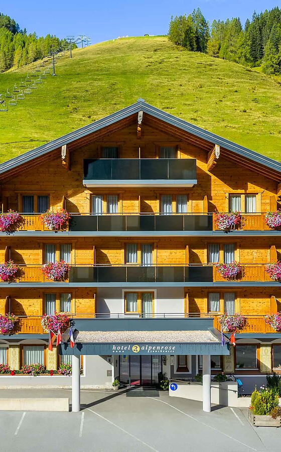 Facade of the Sport & Wellness Hotel Alpenrose in Zauchensee in summer with blooming balcony flowers